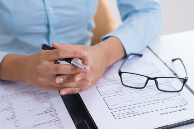 Closeup of boss reading filled application form. Business person sitting at desk. Recruitment concept. Cropped front view.