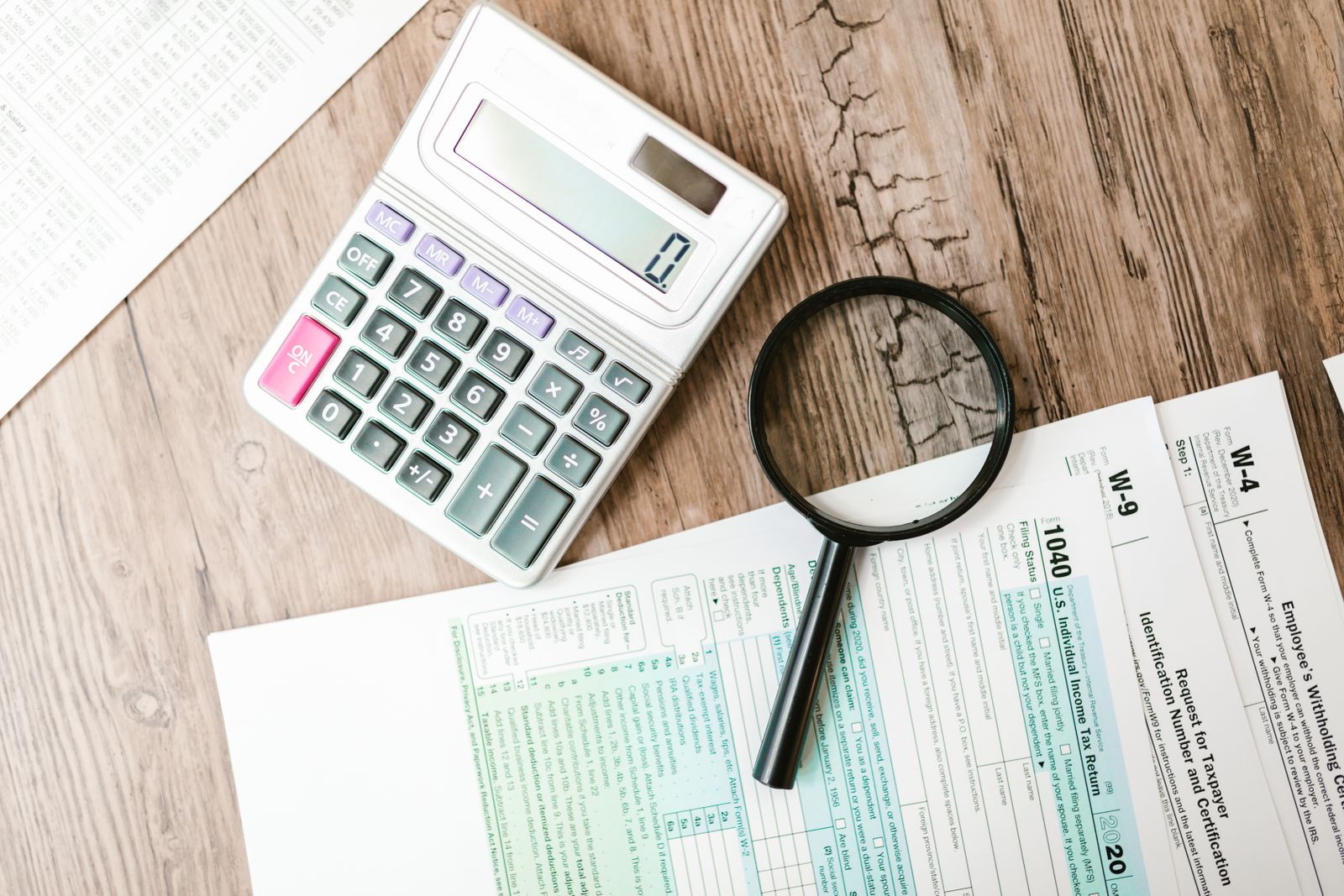 Tax forms and a calculator illustrating how phantom stock is taxed as ordinary W-2 income at payout